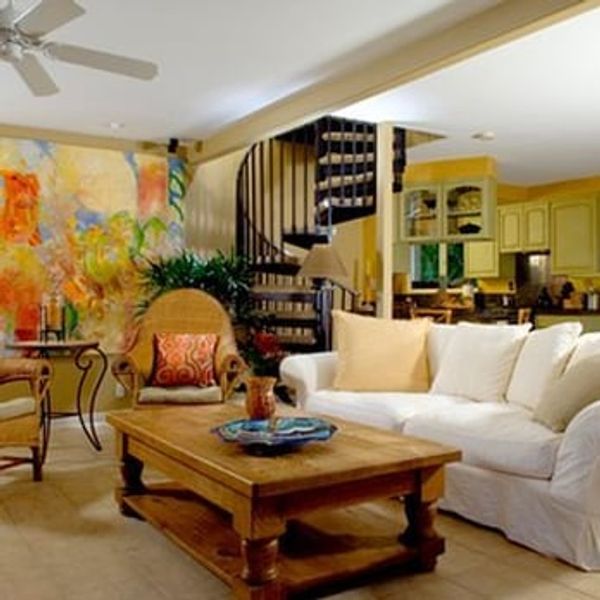 Cozy living room with white sofa, wooden table, and spiral staircase.