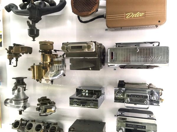 A display of vintage car radios and mechanical parts arranged on a white surface.