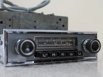 Vintage car radio with tuning dials and preset buttons.