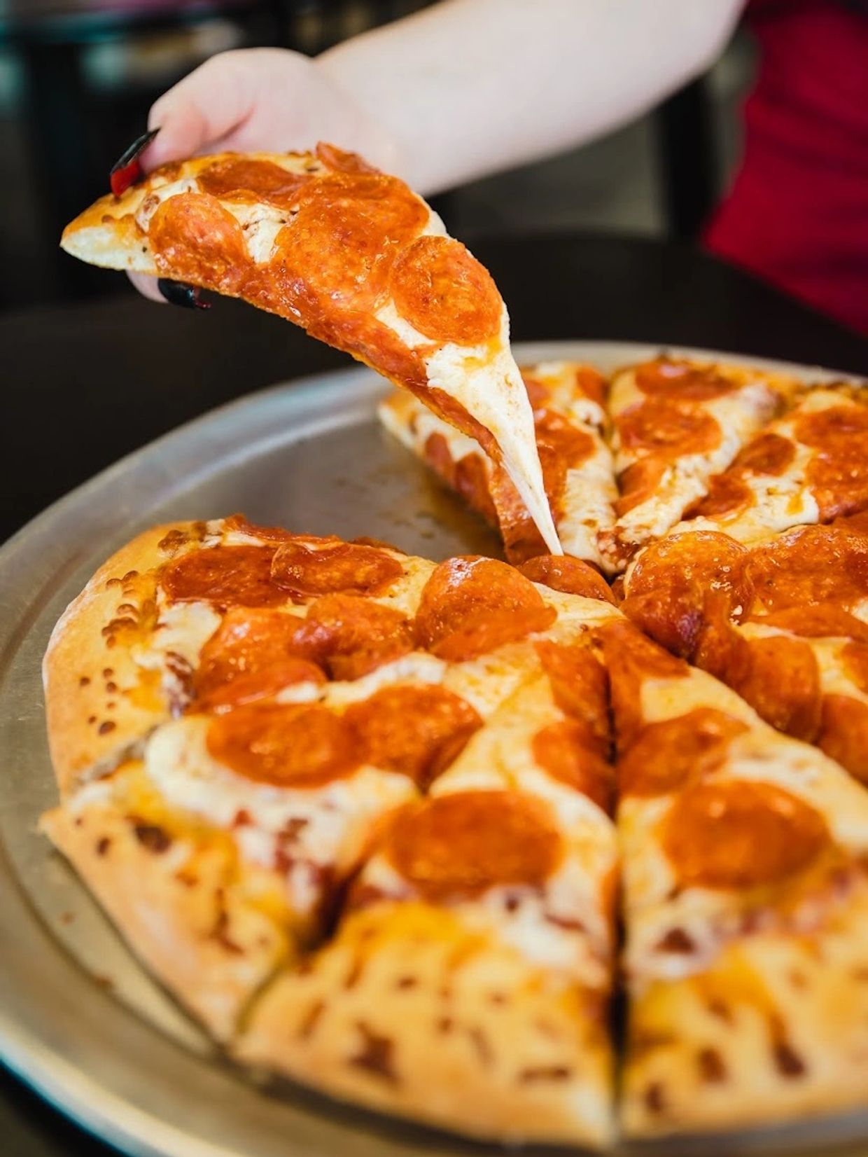 a hand picking up a pizza slice