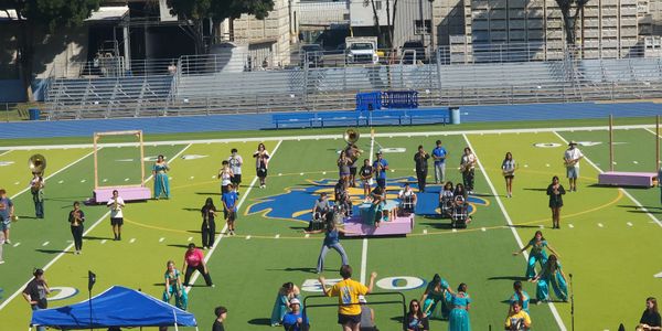 Marching band performing on a football field with colorful uniforms and instruments.