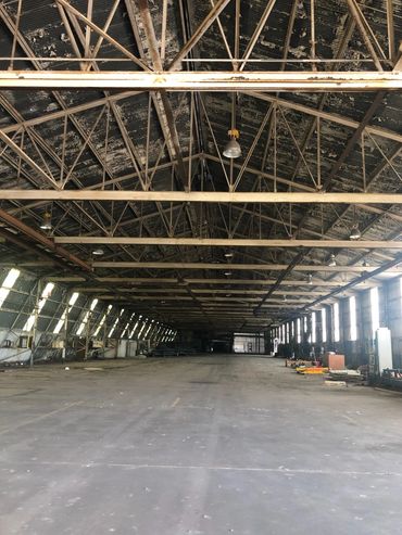 Large empty industrial warehouse with metal beams and peeling paint.