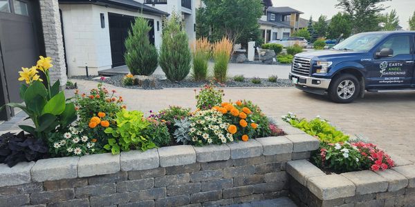 Raised garden bed in front of house with annuals in bloom.