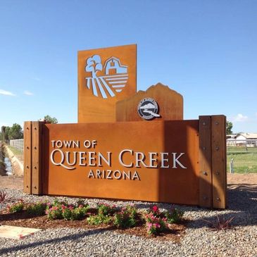 Welcome sign for the Town of Queen Creek, Arizona under a clear blue sky.