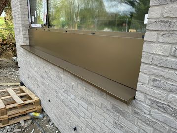 Appui de fenêtre en métal sur une façade en briques.
