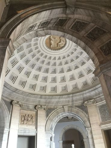 Intricate marble dome with classical reliefs and arches in historic architecture.