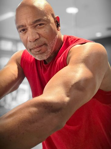 Man in a red sleeveless shirt working out.