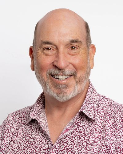Smiling bald man with a patterned shirt.