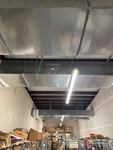 Warehouse ceiling with ductwork and fluorescent lights.