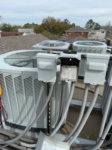Multiple outdoor HVAC units with electrical boxes on a rooftop.
