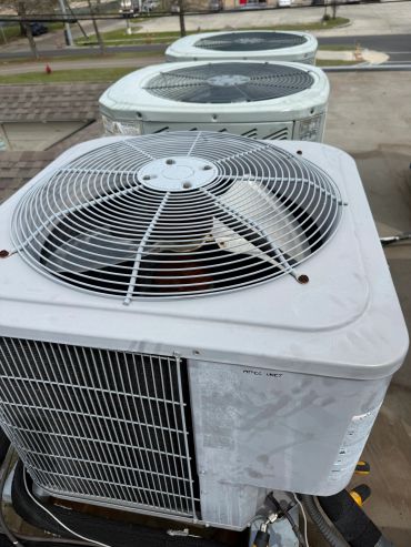 Three outdoor HVAC units lined up outdoors.
