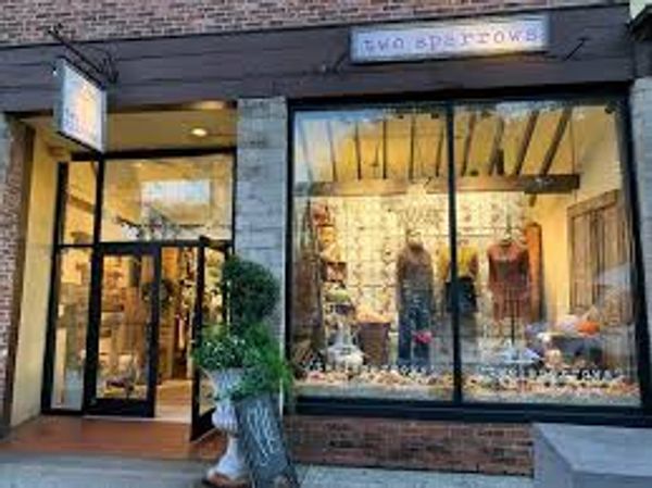 Shopfront window with mannequins and autumn decor.