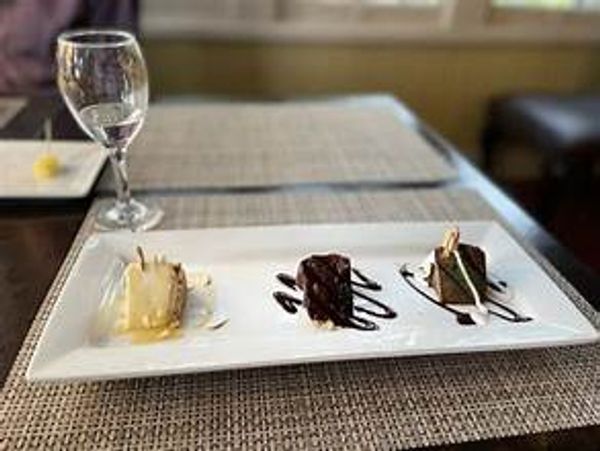 Three mini desserts artistically plated on a white rectangular dish.