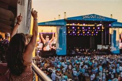 A woman enjoying a live concert with hands raised in excitement.