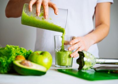 A picture of a person preparing a detox smoothie made of lettuce, avocado and green apple
