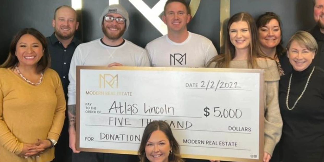 Group holding donation check for $5,000 to Atlas Lincoln.