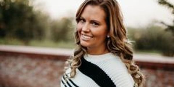 Smiling woman with curled hair outdoors.