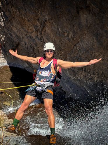 hombre realiza canyoning en Chile con equipo de seguridad, extiende sus manos.