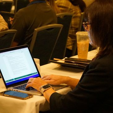 Person typing on a laptop at a conference or meeting.