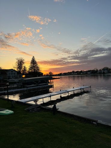 A dock with a boat in the water at sunset.