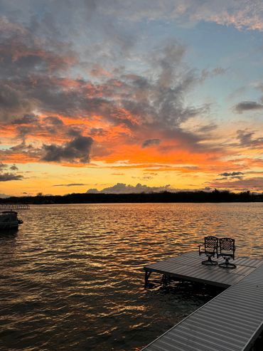A dock with two benches on it at sunset.