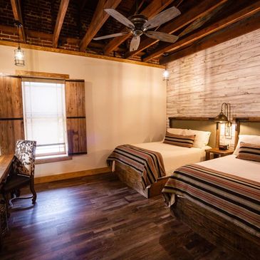 Rustic bedroom with two beds and wooden ceiling beams.