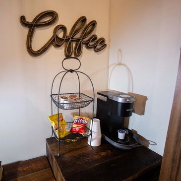 Cozy coffee station with a Keurig machine and snacks on a wooden table.