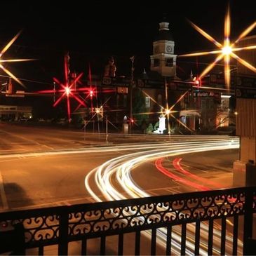 Long exposure of car lights at a night intersection with starburst streetlights.