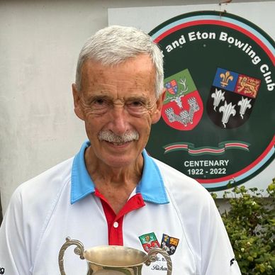 Elderly man holding a trophy at a bowling club.
