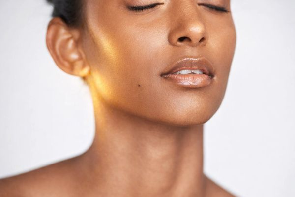 Close-up of a serene woman with glowing skin and closed eyes.