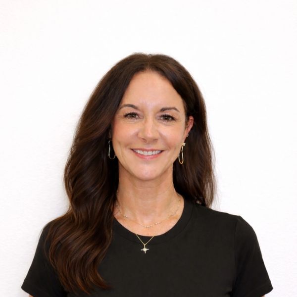 Smiling woman with long dark hair wearing a black shirt and gold jewelry.