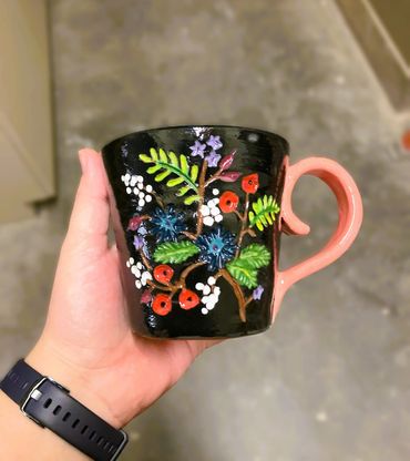 black mug with carved and painted flowers