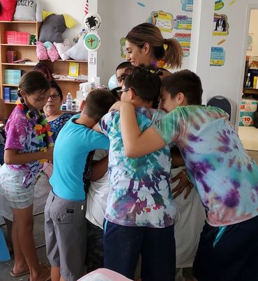 Children gathered around a woman in a colorful room, engaged and curious.
