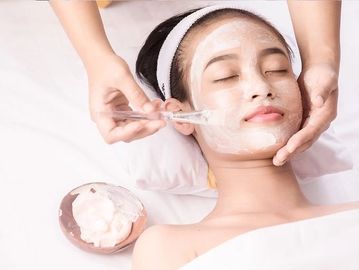 A beautician is applying facial on the client face