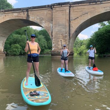 Stand up paddleboarders in front of bridge