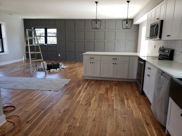 Modern kitchen with wooden floors and gray accent wall under renovation.