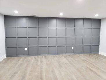 Modern room with gray paneled wall and light wood flooring.
