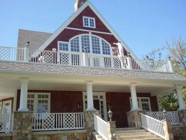 Large house with a spacious porch and balcony under a clear sky.