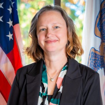Professional woman smiling in front of flags.
