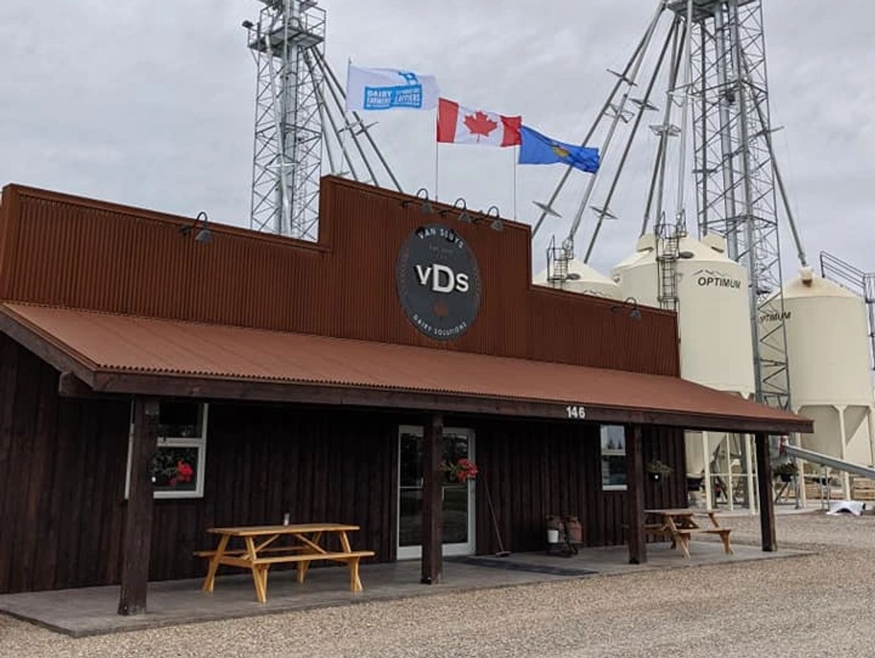 Exterior of Van Suyt Dairy Solutions building with flags and silos.