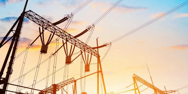 Electric power lines and towers against a sunset sky.