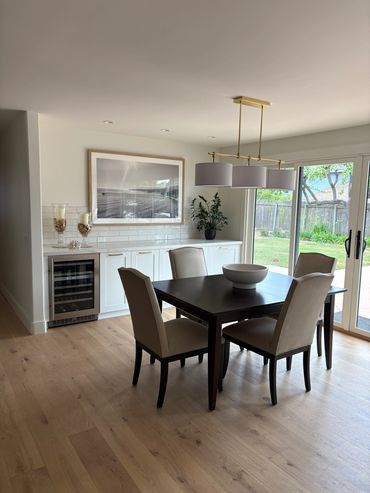 Elegant dining area with dark wood table, beige chairs, and natural light from sliding doors.
