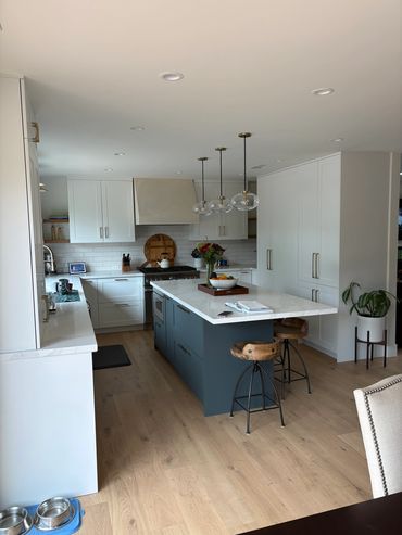 Modern kitchen with white cabinets and wooden stools around a blue island.