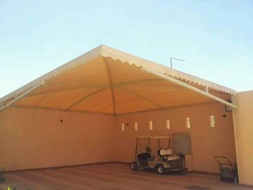 Covered parking area with a small vehicle and lawnmower.