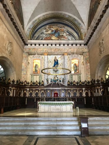 Ornate altar with religious statues and frescoes inside a historic church.