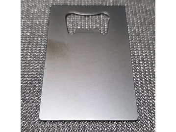Close-up of a metal bottle opener on a textured surface.