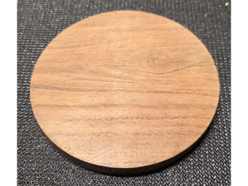 Close-up of a wooden round coaster on a textured black surface.