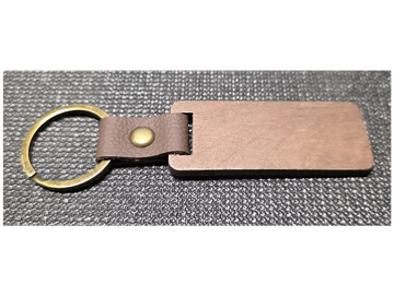 Rectangular wooden keychain with leather strap and brass ring on black surface.