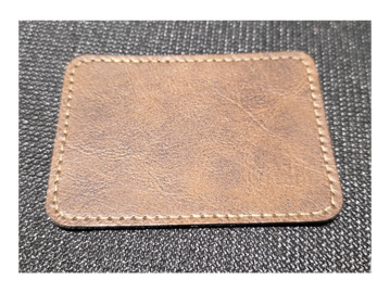 A rectangular piece of brown leather with stitching around the edges.