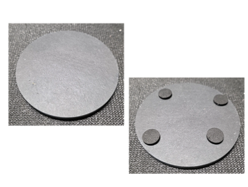 Two images showing a black circular base, one plain and one with four black adhesive pads attached.